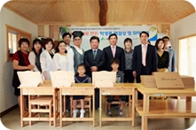 기증받은 학생용 책상과 의자로 채워진 교실에서 함께 찍은 기념사진